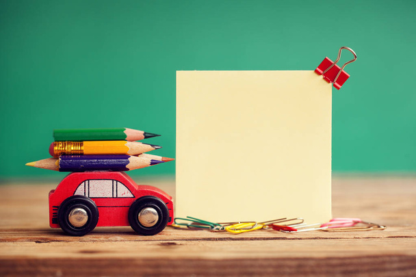 Miniature Red Car Carrying a colorful pencils on wooden table and place for text. Back to school concept. - Zdjęcie, obraz