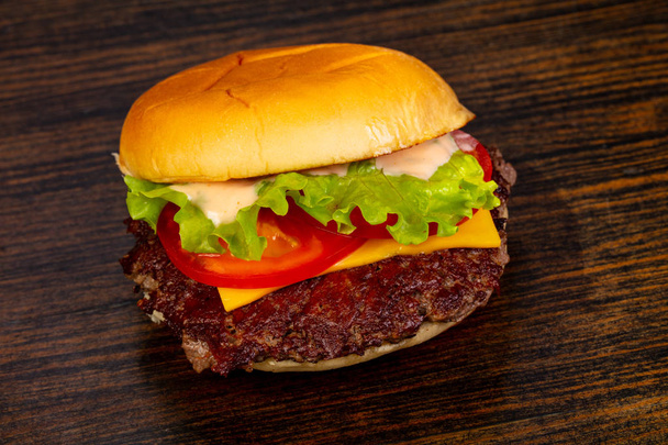 Ahşap arka plan üzerinde lezzetli sıcak burger - Fotoğraf, Görsel
