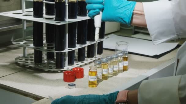 laboratorní asistent bere malá žlutá tekutina s přístrojem - Záběry, video