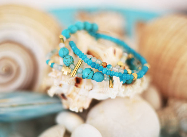 close-up de turquesa e ágata pulseiras de pedra preciosa - fundo embaçado com conchas
 - Foto, Imagem