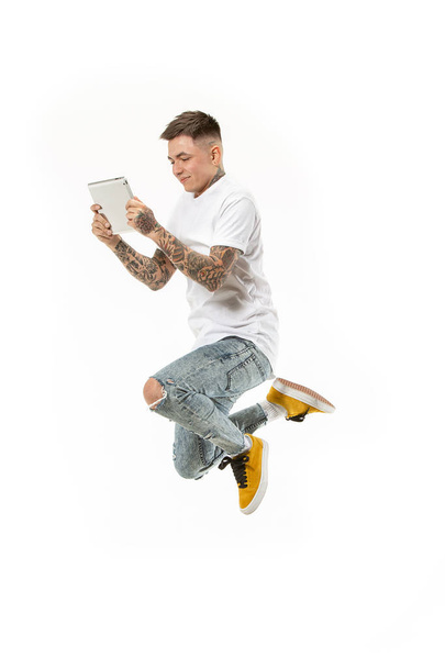 Immagine di giovane uomo su sfondo bianco utilizzando il computer portatile durante il salto
. - Foto, immagini