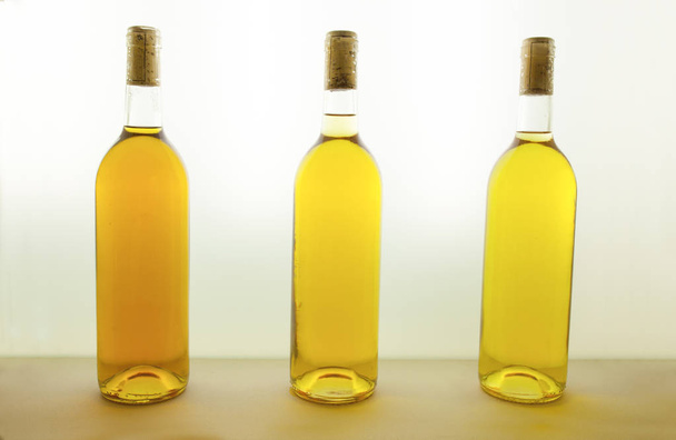 drei Flaschen Weißwein in verschiedenen Tönen. Weinfarbenkonzept  - Foto, Bild