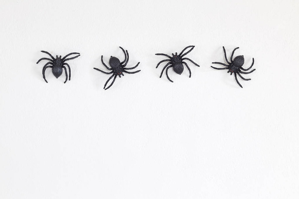 Grandes aranhas de brinquedo preto em uma parede fundo branco para halloween, espaço de cópia, Flat lay
 - Foto, Imagem