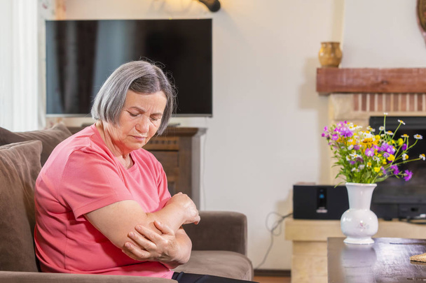 Senior kobieta cierpi na ból w ręce w domu. Starość, problem i ludzi pojęcie zdrowia  - Zdjęcie, obraz