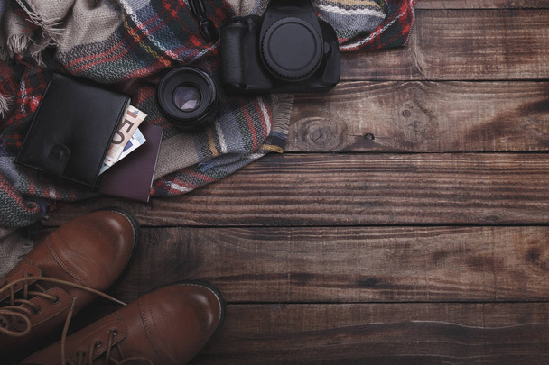 Traveler's photographer's accessories camera lense boots thermos purse with money plaid and notepad on old barn wood background - Foto, Imagem