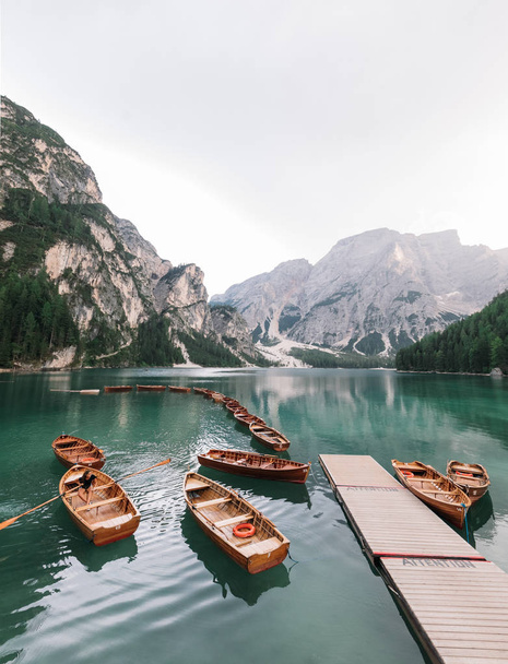 majestic view of pier with wooden boats at beautiful lake in mountains, Lago di Braies, Italy - Fotoğraf, Görsel