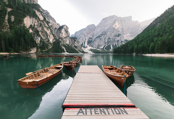 majestic view of pier with wooden boats at beautiful lake in mountains, Lago di Braies, Italy - Фото, зображення