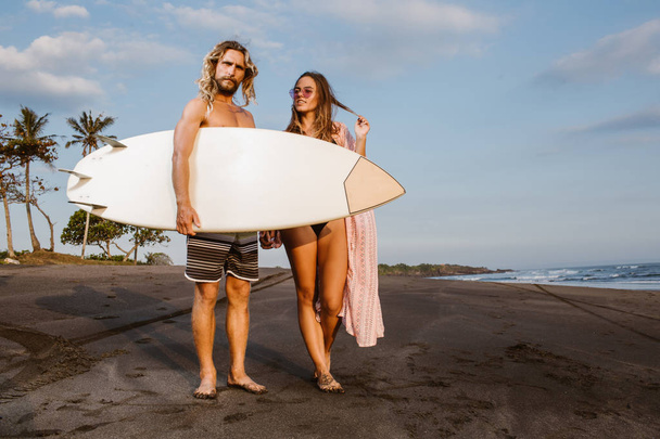 couple standing with surfboard on beach in bali, indonesia - Foto, Imagem