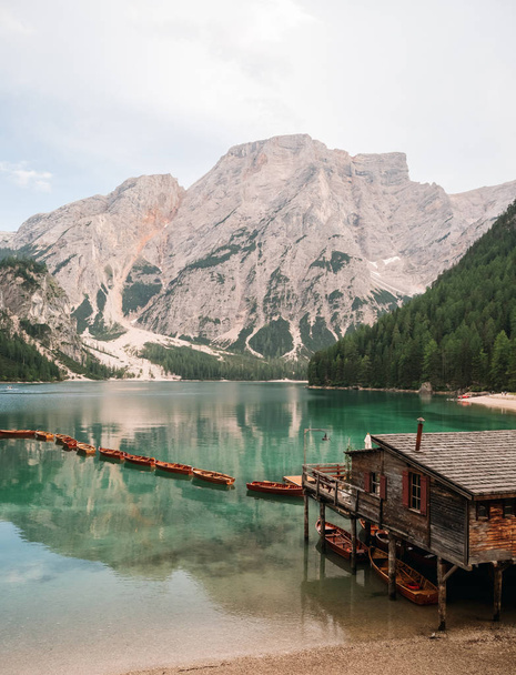 majestic view of pier with wooden boats at beautiful lake in mountains, Lago di Braies, Italy - Foto, imagen