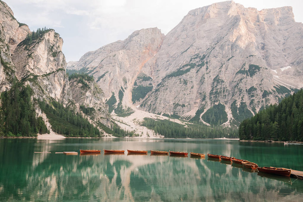 majestic view of pier with wooden boats at beautiful lake in mountains, Lago di Braies, Italy - Foto, Imagem