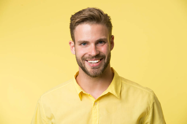 Brilliant smile. Man smiling face posing confidently yellow background. Man shop consultant looks cheerful confident and hospitable. Guy with bristle glad to help you in shop. Sincere emotions - Zdjęcie, obraz