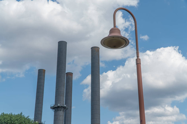 Pohled při pohledu na staré továrny kouřové komíny s starožitné lampy v popředí proti pěkný den čas obloha pozadí stran oblačné počasí - Fotografie, Obrázek