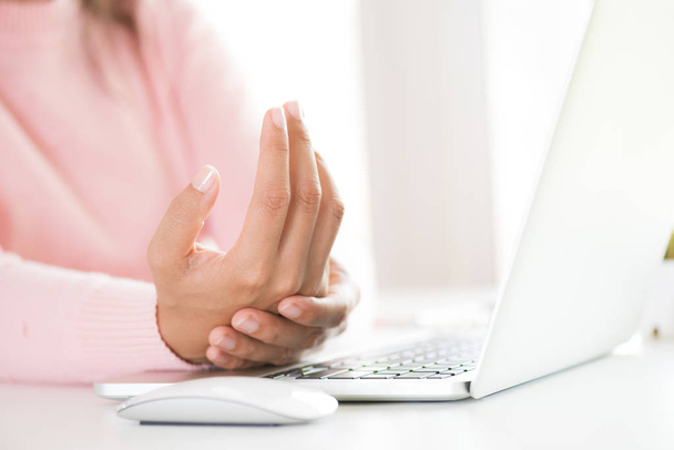 Mujer de primer plano sosteniendo su dolor de muñeca de usar la computadora. Síndrome de oficina dolor de manos por enfermedad ocupacional
. - Foto, imagen