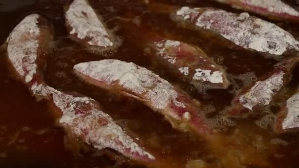 Κοντινό πλάνο μαγειρέματος βαθιά τηγανητό κόκκινο βασιλιά Κέφαλος ψάρι στο καυτό καυτό λάδι σε μεγάλο τηγάνι, μεγάλη γωνία προβολής - Πλάνα, βίντεο