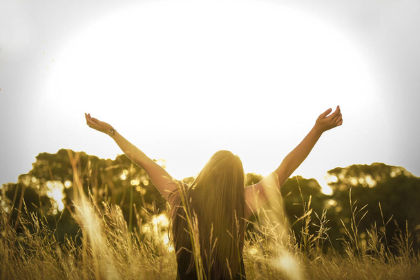 young woman with outstretched arms at wild field - 写真・画像