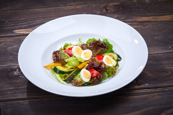 овощной салат с яйцом на белой тарелке, крупным планом
  - Фото, изображение