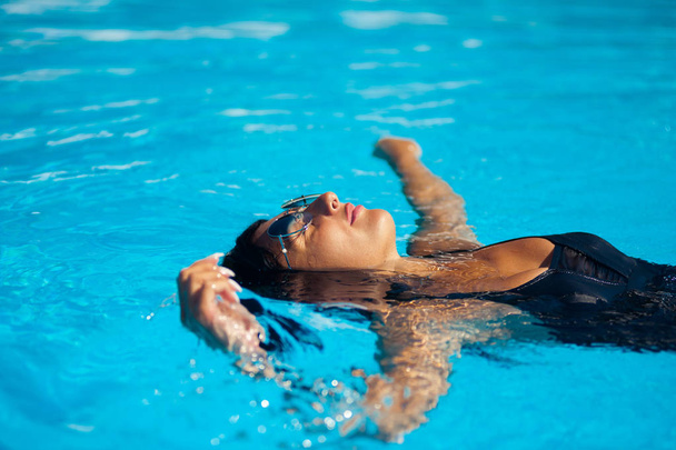 Elegante mujer sexy en el bikini en el cuerpo delgado y bien formado bronceado por el sol está posando cerca de la piscina
 - Foto, imagen