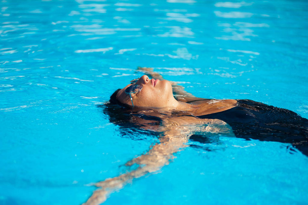 Elegant sexy woman in the bikini on the sun-tanned slim and shapely body is posing near the swimming pool - Фото, зображення