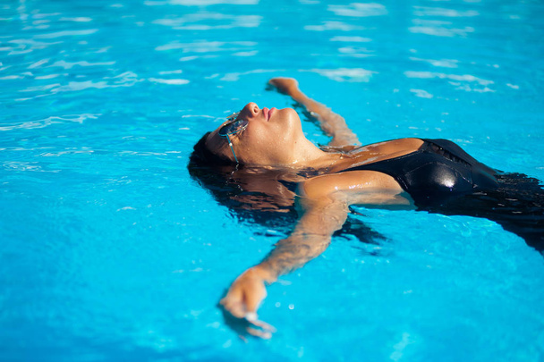 Elegante mujer sexy en el bikini en el cuerpo delgado y bien formado bronceado por el sol está posando cerca de la piscina
 - Foto, Imagen