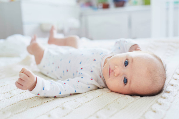 Adorable baby girl lying on bed. Infant kid in sunny nursery - Foto, afbeelding