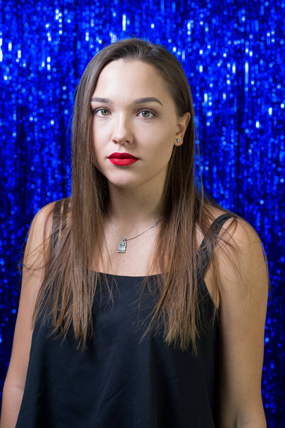 beaty girl with red lipstick on her lips posing on the camera against the background of shiny blue sequins - Foto, immagini
