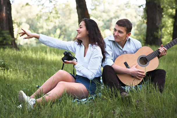 Młoda para spaceru w lesie i gra na gitarze, biorąc zdjęcie na starym aparatem, lato natura, jasne światło słoneczne, cienie i zielonych liści, romantyczne uczucia - Zdjęcie, obraz