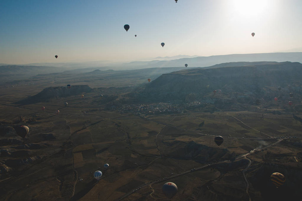 Goreme, Turkey. April 5, 2018: Colorful balloons flying over mountains and with blue sky - Foto, imagen