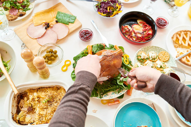 Высокоугловой портрет неузнаваемого человека, режущего курицу во время праздничного семейного торжества дома, фокусирующегося на еде, копировальном пространстве
 - Фото, изображение