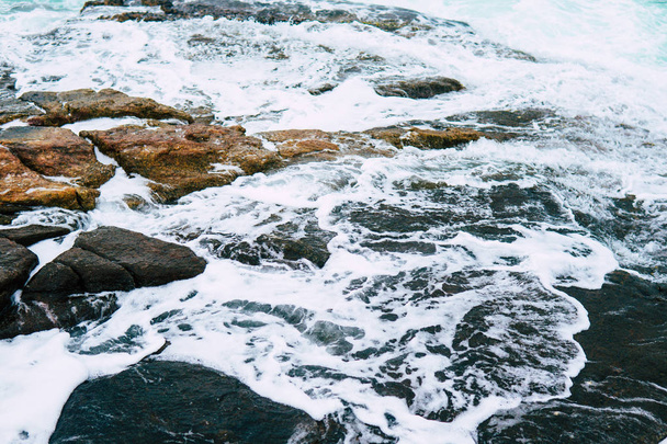 Blue waves crashing on a rocky shore close up - Valokuva, kuva