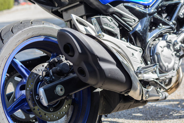 Крупный план мотоцикла показывает двойной выхлоп с глушителем и тормозным диском
 - Фото, изображение