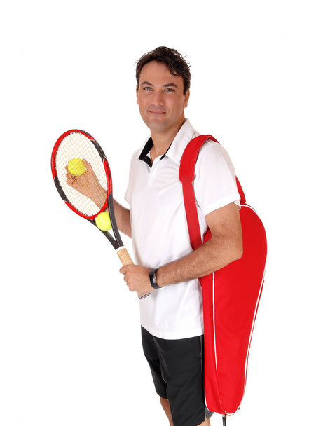 Egy jóképű fiatal férfi állandó a tenisz felszerelés, teniszütő és labda - Fotó, kép