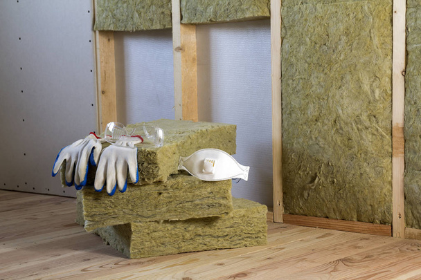 Rock wool and fiberglass insulation staff material for cold barrier. Tools for work with glass wool: protective goggles, glasses and mask. Warm home, economy, construction and renovation concept. - Photo, Image