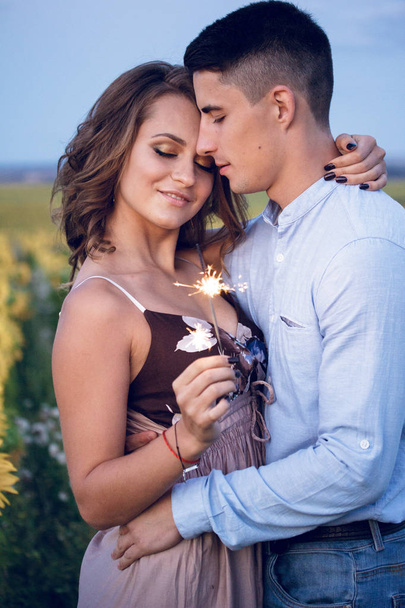 幸せなカップルは、ひまわり背景にベンガル花火を開催します。夜間休日の夜 - 写真・画像