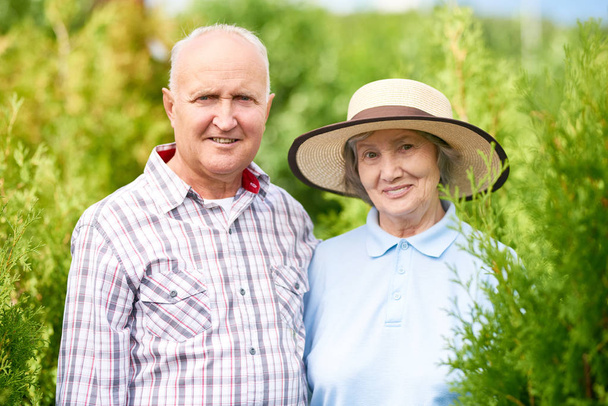 Portré szerető idős házaspár kerti kamera nézett és mosolyogva pózol - Fotó, kép