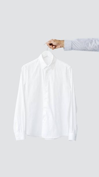 männliche Hand hält Kleiderbügel mit Shirt - Foto, Bild