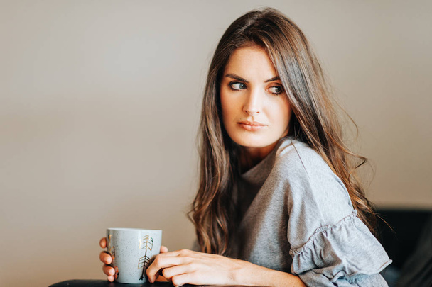 Jeune belle femme reposant sur le canapé, tenant une tasse de thé
 - Photo, image