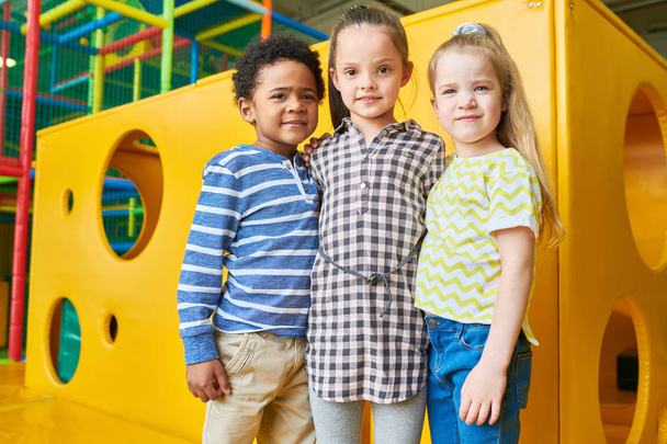 Retrato de grupo multi-étnico de crianças posando por queijo amarelo como caixa se divertindo na área de jogo
 - Foto, Imagem