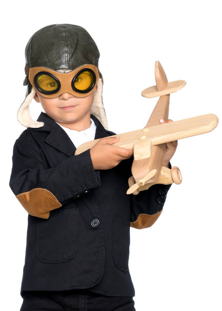 Kleiner Junge mit einem hölzernen Flugzeug. - Foto, Bild