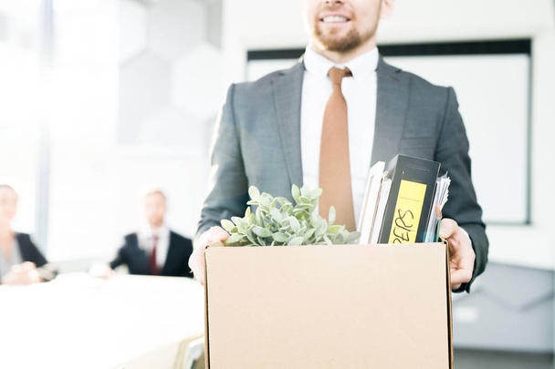 Porträt eines lächelnden Geschäftsmannes mit einer Schachtel voller persönlicher Gegenstände, der sein Amt verlässt, nachdem er seinen Job aufgegeben hat, Kopierraum - Foto, Bild