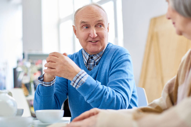 Portrait of nice senior couple enjoying conversation while drinking tea at home, focus on balding elderly man talking to wife, copy space - Fotografie, Obrázek