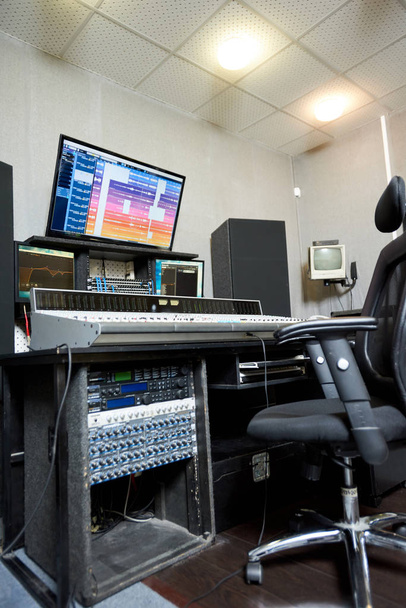 Vista desde abajo de la consola de trabajo con monitores y electrónica musical en estudio de sonido
. - Foto, Imagen