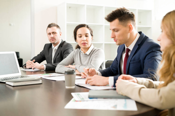 Portrait of business people sitting in row at meeting table in conference room discussing work and planning strategy - 写真・画像