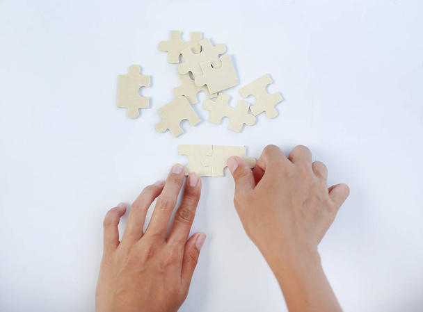 Closeup hands connecting jigsaw puzzle on white background - Fotografie, Obrázek
