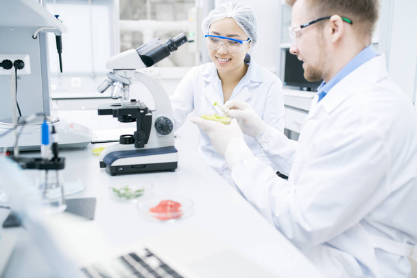 Portret dwóch nowoczesnych młodych naukowców uśmiechający się podczas prowadzenia badań badania w laboratorium, miejsce do żywności substancji - Zdjęcie, obraz