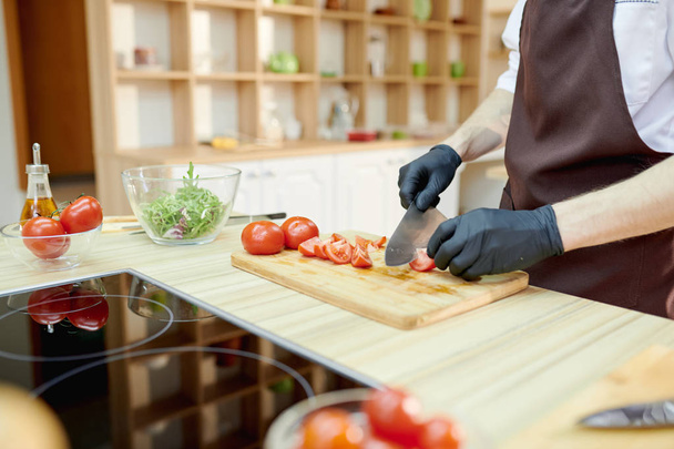 Primo piano di irriconoscibile chef maschio tagliare verdure in piedi al tavolo di legno in cucina ristorante, spazio copia
 - Foto, immagini