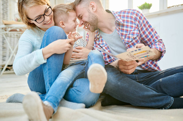 Babalar günü birlikte kutluyor oturma odasında katta oturan sevimli oğlu ile oynarken mutlu sevgi dolu aile sıcak tonlu portresi - Fotoğraf, Görsel