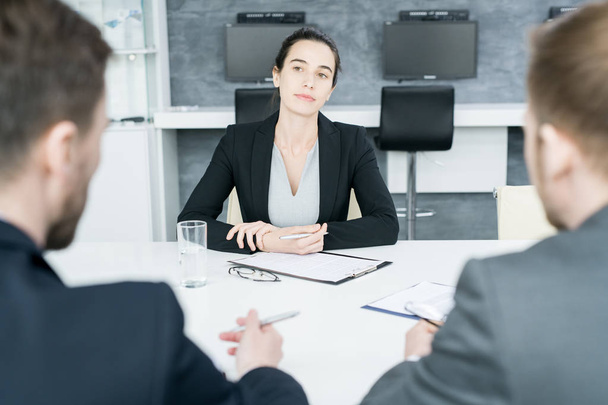 Retrato de empresária confiante dirigindo reunião ouvindo parceiros sentados em frente à mesa na sala de conferências
 - Foto, Imagem