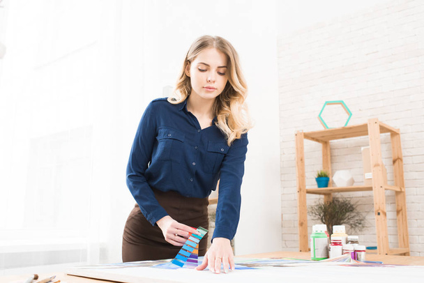 junge Frau arbeitet in Werkstatt mit Mustern - Foto, Bild