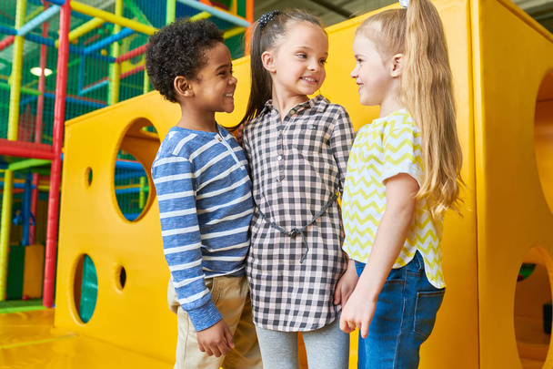 Retrato de grupo multi-étnico de crianças em pé por queijo amarelo como caixa se divertindo na área de jogo
 - Foto, Imagem