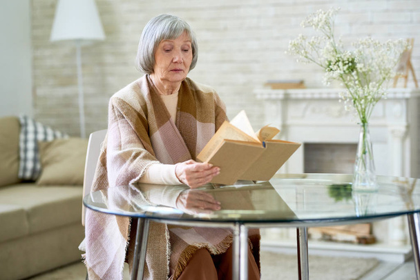 Szép vezető hölgy portréja ül otthon, üveg asztal könyvével kockás sál csomagolva másol hely - Fotó, kép